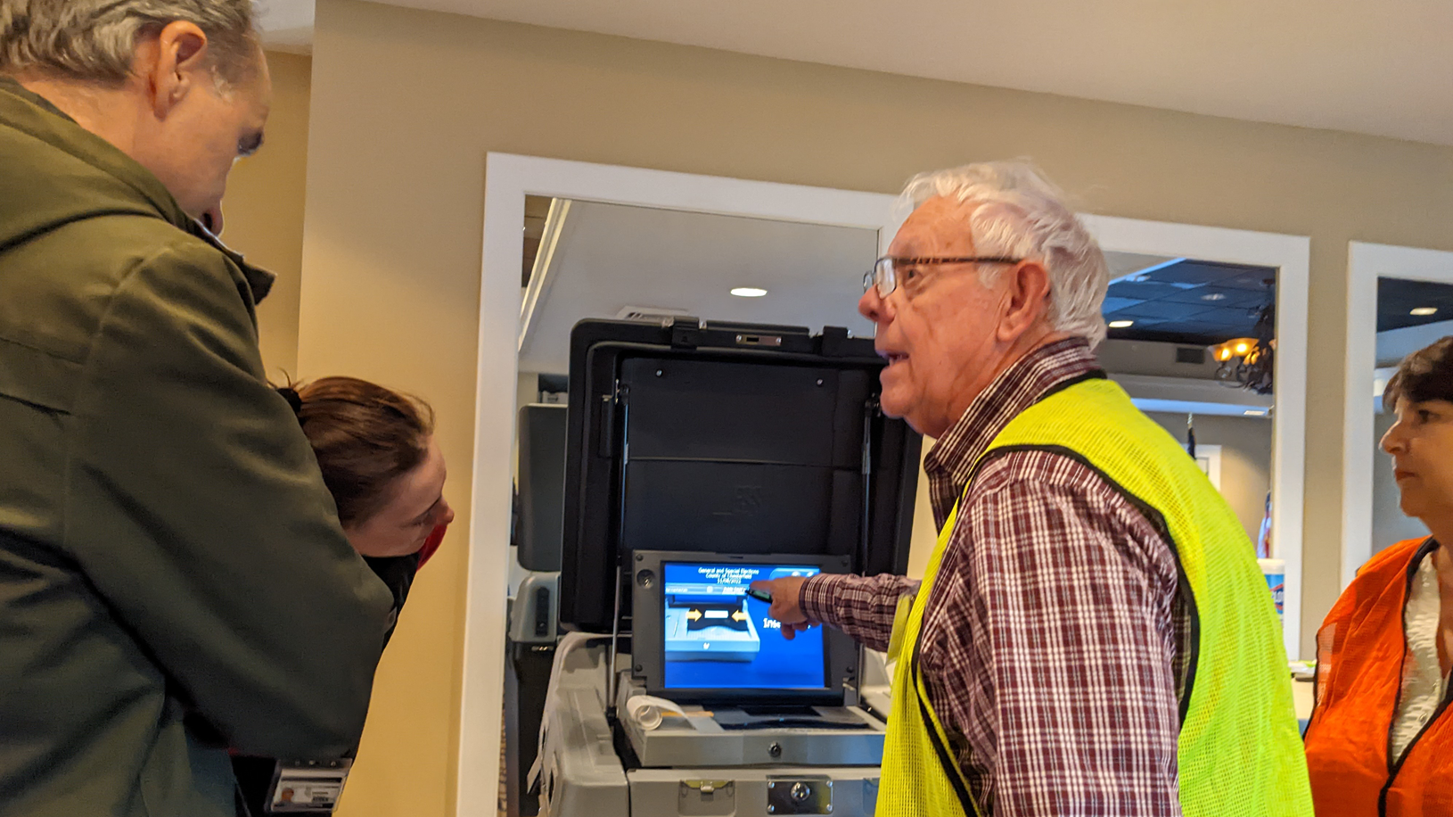 A poll worker demonstrates how to use a voting machine