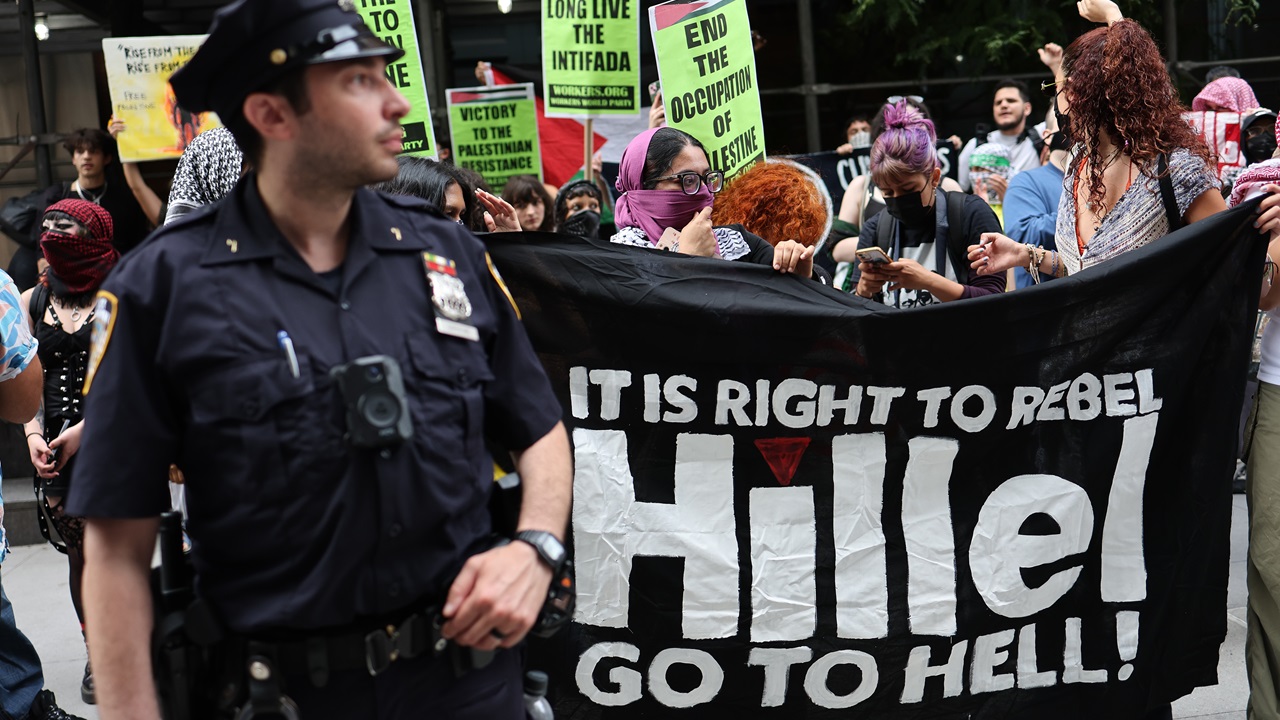 Protesters demonstrate against Hillel at Baruch College in New York, NY on June 5, 2024. The banner reads "It's right to rebel, Hillel go to hell!" with an inverted red triangle over the i in Hillel.