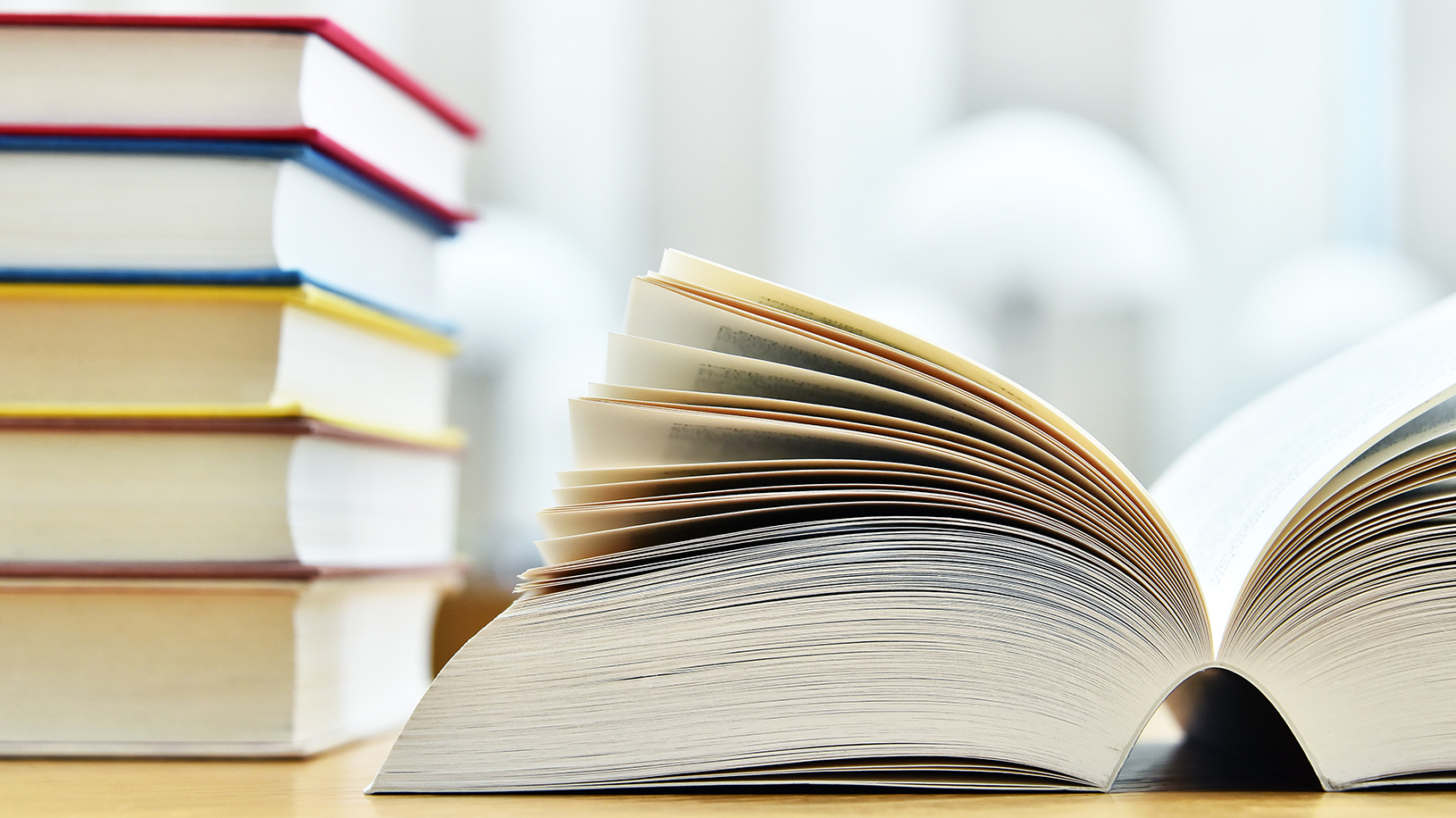 Library books on a table with a book open to the center