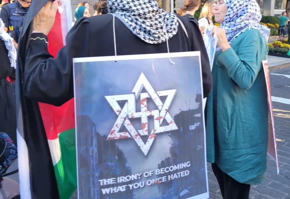 Placard worn by a protester in Washington, DC, on October 5, 2024, reads: “The Irony of Becoming What You Once Hated,” with a bloodied Jewish start overlapping a Nazi swastika. (source: X)