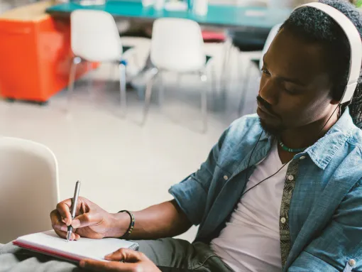 African man podcasting and taking notes