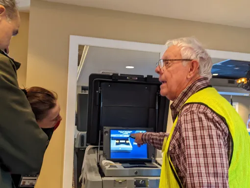 A poll worker demonstrates how to use a voting machine