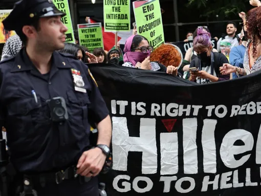 Protesters demonstrate against Hillel at Baruch College in New York, NY on June 5, 2024. The banner reads "It's right to rebel, Hillel go to hell!" with an inverted red triangle over the i in Hillel.